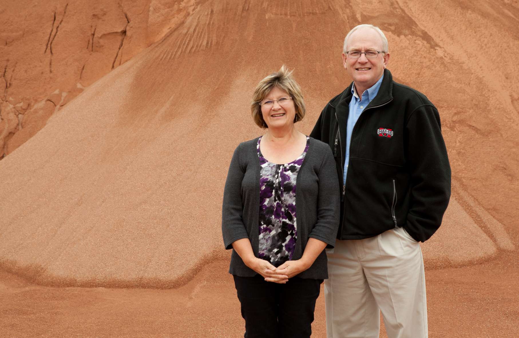 Mar-Co team members standing in front of a pile of clay materials smiling at the camera