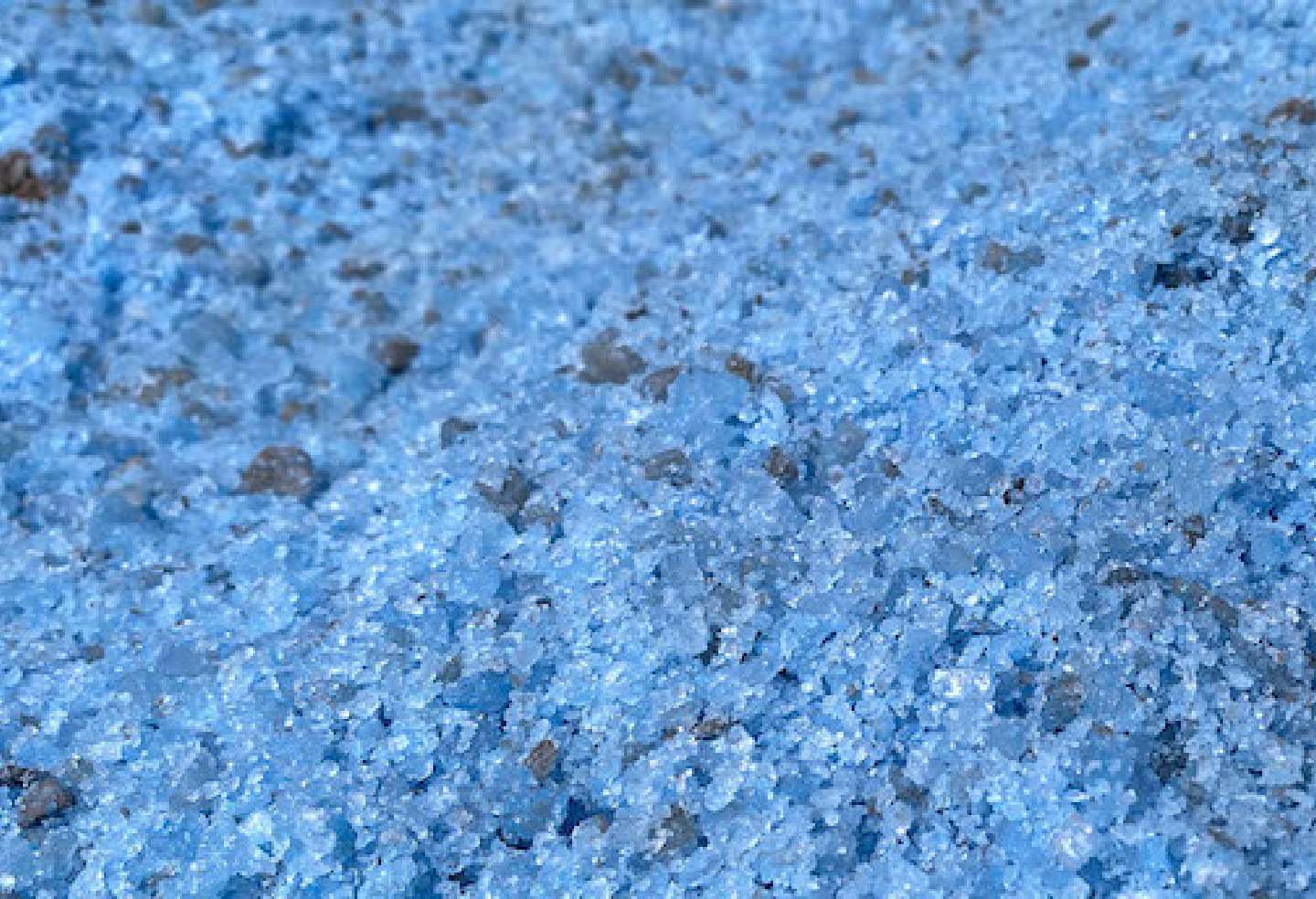 Blue Thawrox crystals dispersed on gravel